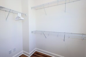 Ein Zimmer mit weißen Wänden, Holzboden und drei an der Wand befestigten Metalltrocknergestellen.