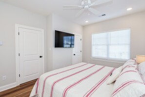 A bedroom with a bed, a ceiling fan, a mounted TV, and a window with blinds. - Rebel Retreat - Close to the Square, Campus and MTrade Park! (Oxford)