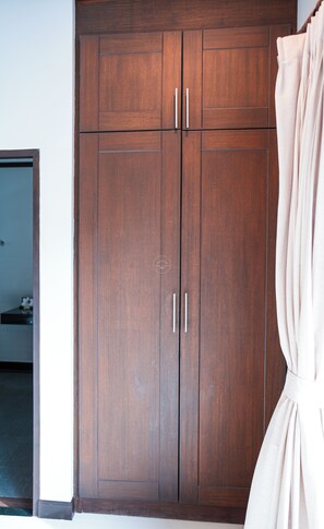 Ein Holzkleiderschrank mit zwei Türen und Griffen, einem Spiegel und einem Vorhang.