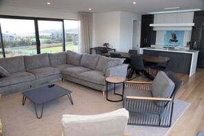 A modern living room with a sectional sofa, a coffee table, and a dining area with a small round table.