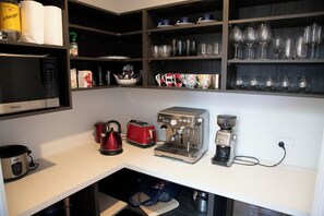 Una cocina compacta con microondas, hervidor, tostadora y cafetera.