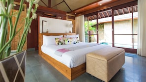 A spacious bedroom with a wooden bed, a large window, and a view of greenery outside. - Bayu Gita Beachfront - 6BR Oceanfront Villa, Cinema, Gym & Huge Pool (Bali)