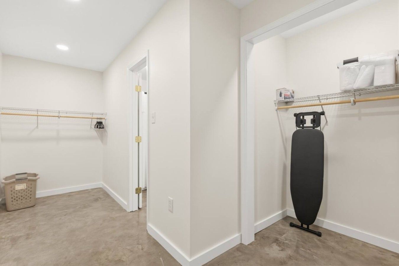 A laundry room with a drying rack, a washing machine, and a trash bin.