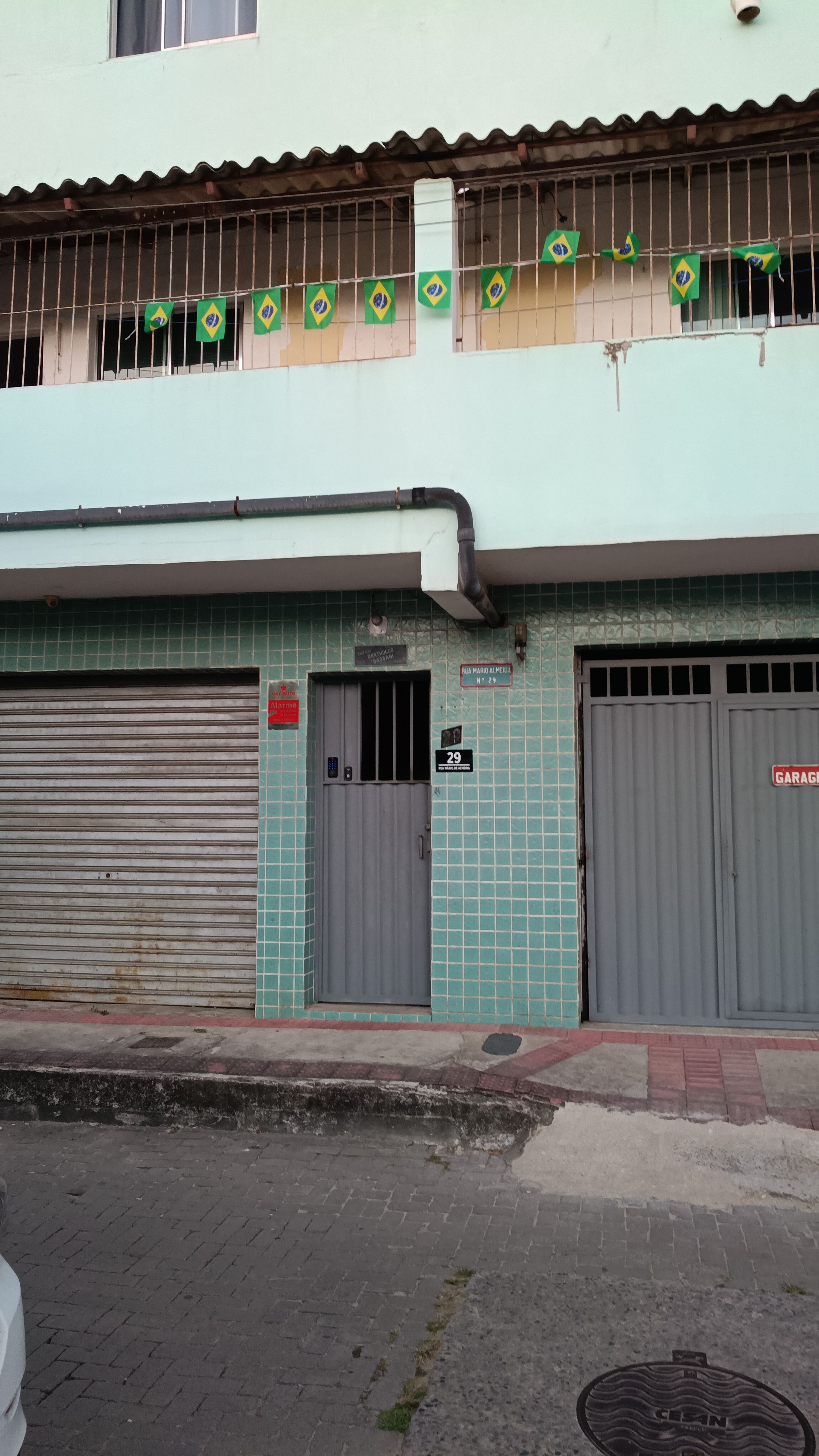 Um edifício com fachada revestida de azulejos, duas portas de garagem fechadas e uma fileira de bandeiras no nível superior.