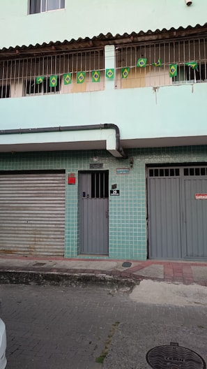 A building with a tiled facade, two closed garage doors, and a row of flags on the upper level.