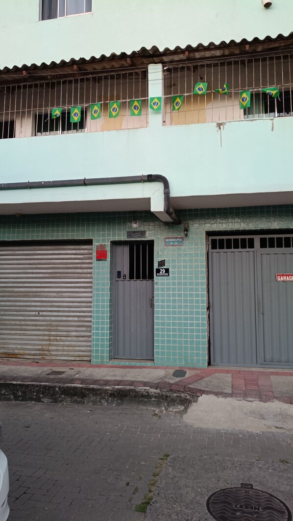 Un edificio con fachada de tejas, dos puertas de garaje cerradas y una hilera de banderas en el nivel superior.