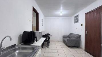 A compact kitchenette with a sink, a coffee maker, and a small table.