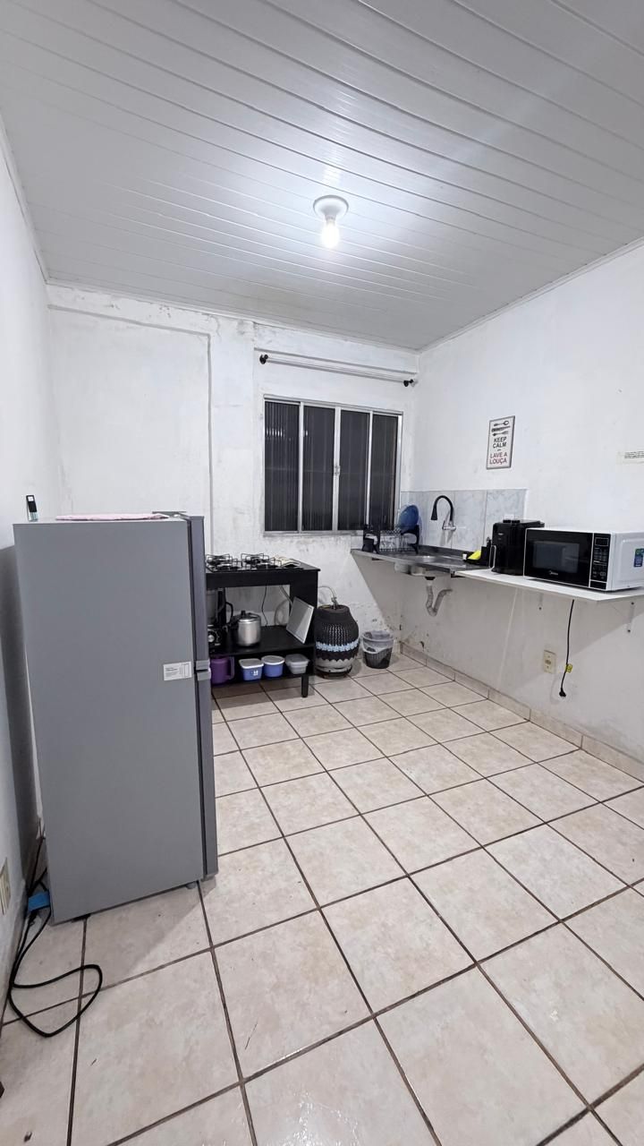 Cozinha compacta equipada com geladeira, fogão a gás, micro-ondas e uma janela com grades.