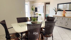 A dining area with a glass table, wicker chairs, and a vase with flowers. - ASA Pe na Areia 3QT Beto Carrero Gravata (Navegantes)
