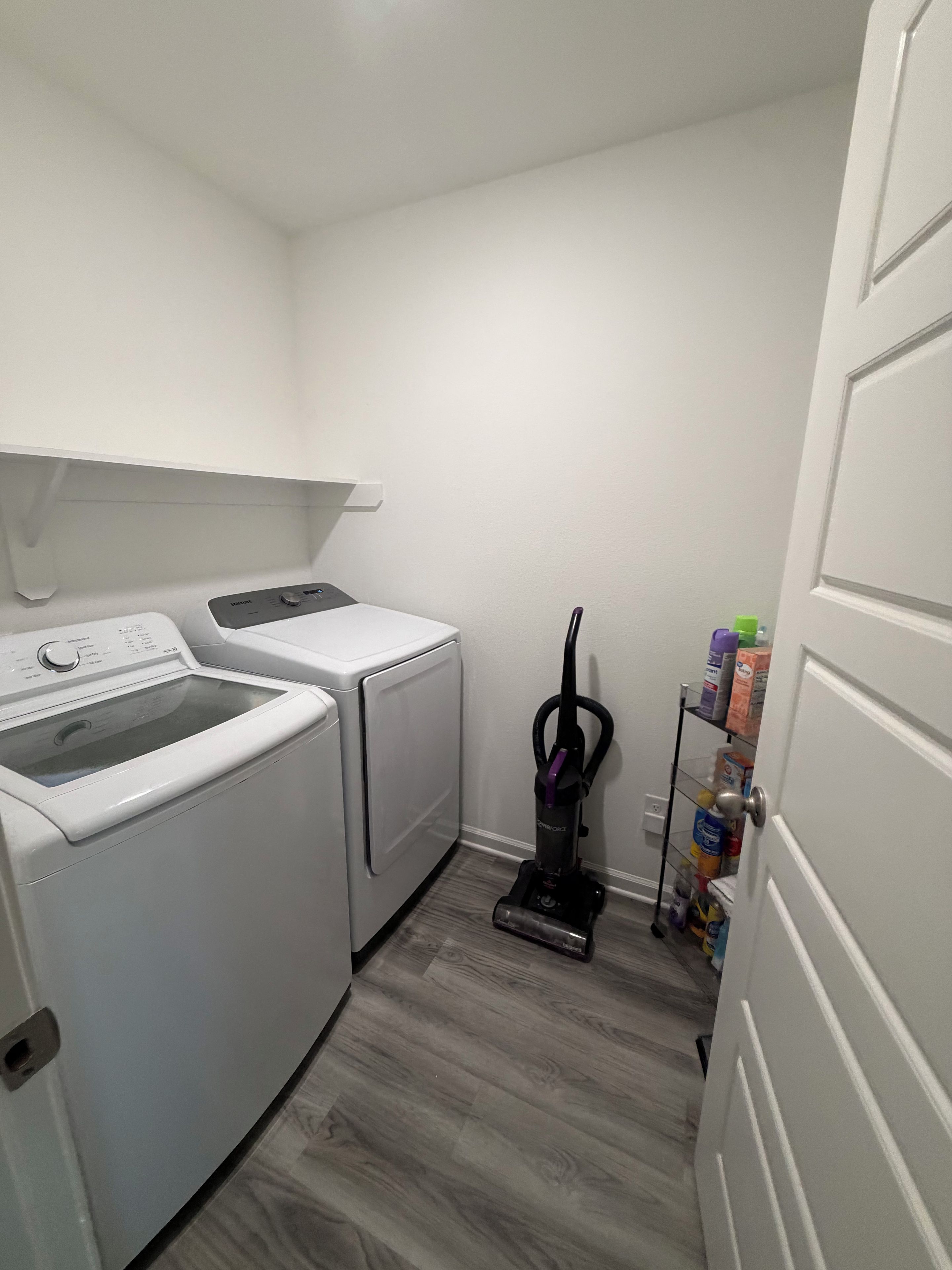 A laundry room with a washing machine, dryer, and vacuum cleaner.