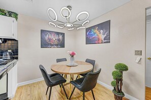 Un comedor con una mesa redonda, sillas negras, un jarrón con flores y dos cuadros colgados en la pared.