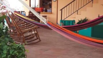 A spacious indoor area with a tiled floor, a hammock, ceiling fans, and a staircase.