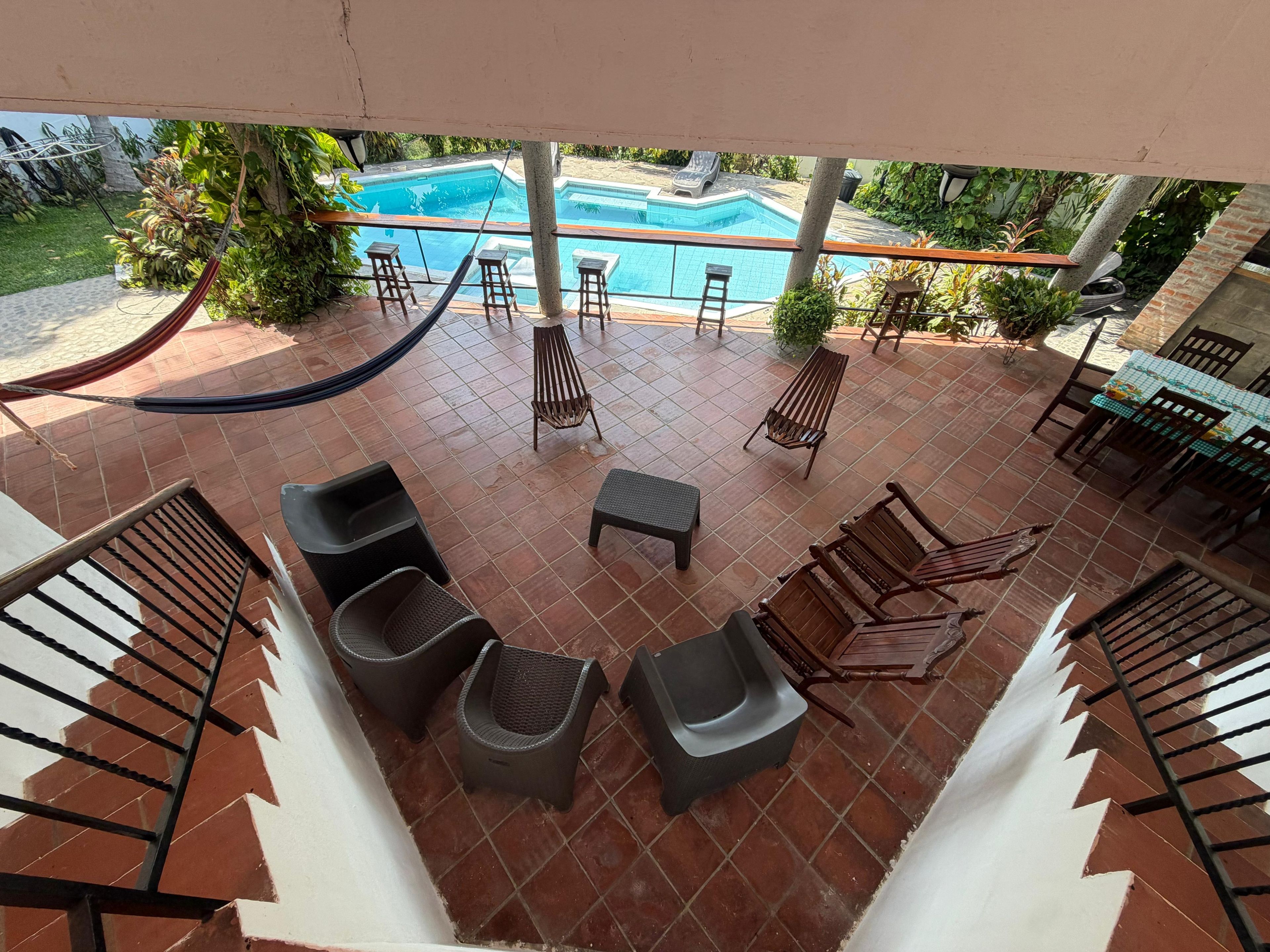 A poolside area with a hammock, lounge chairs, and a table with chairs.