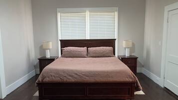 A bedroom with a large bed, two bedside tables, a ceiling fan, and a window with blinds.
