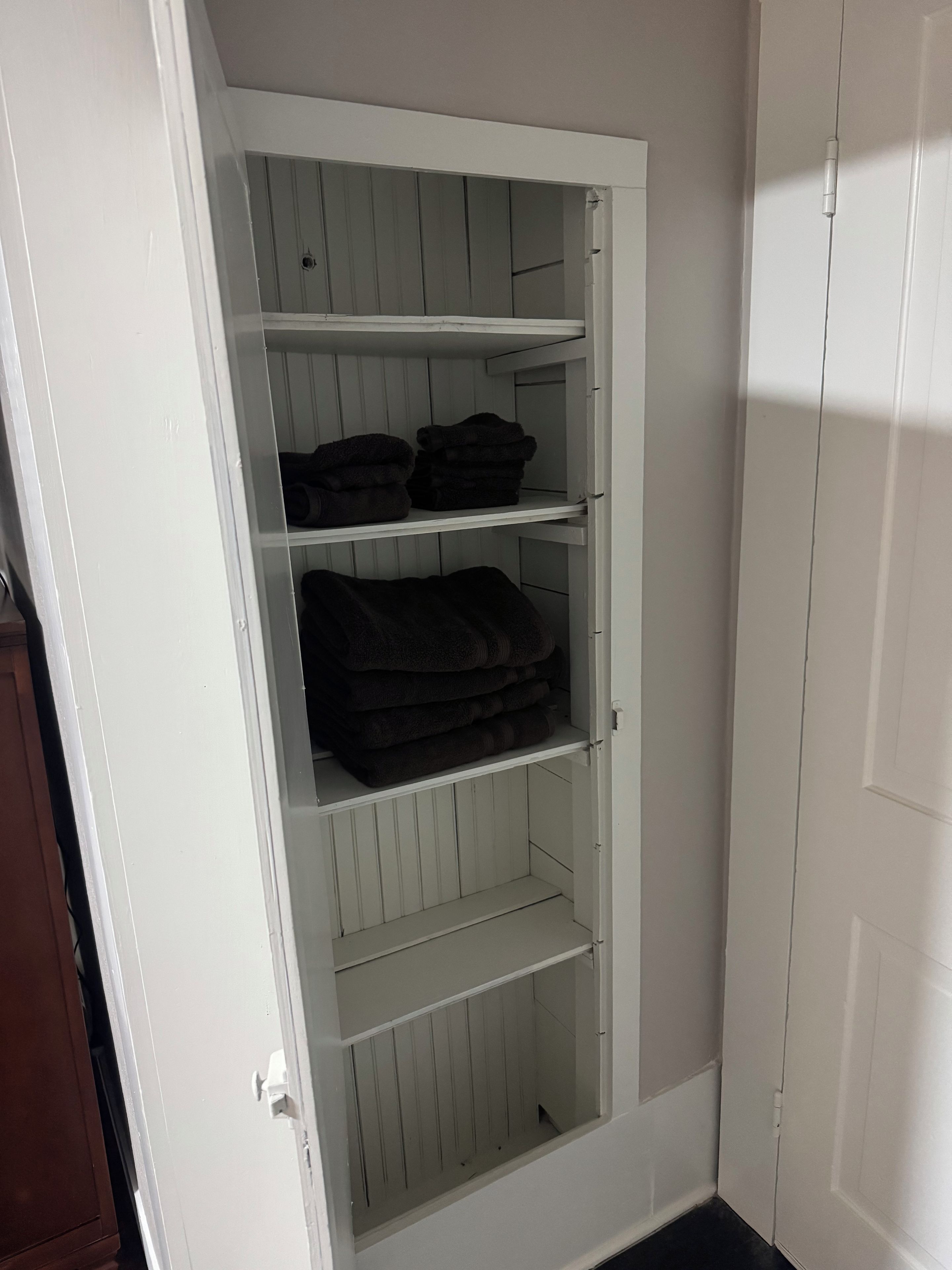 A white wardrobe with multiple shelves and a door.