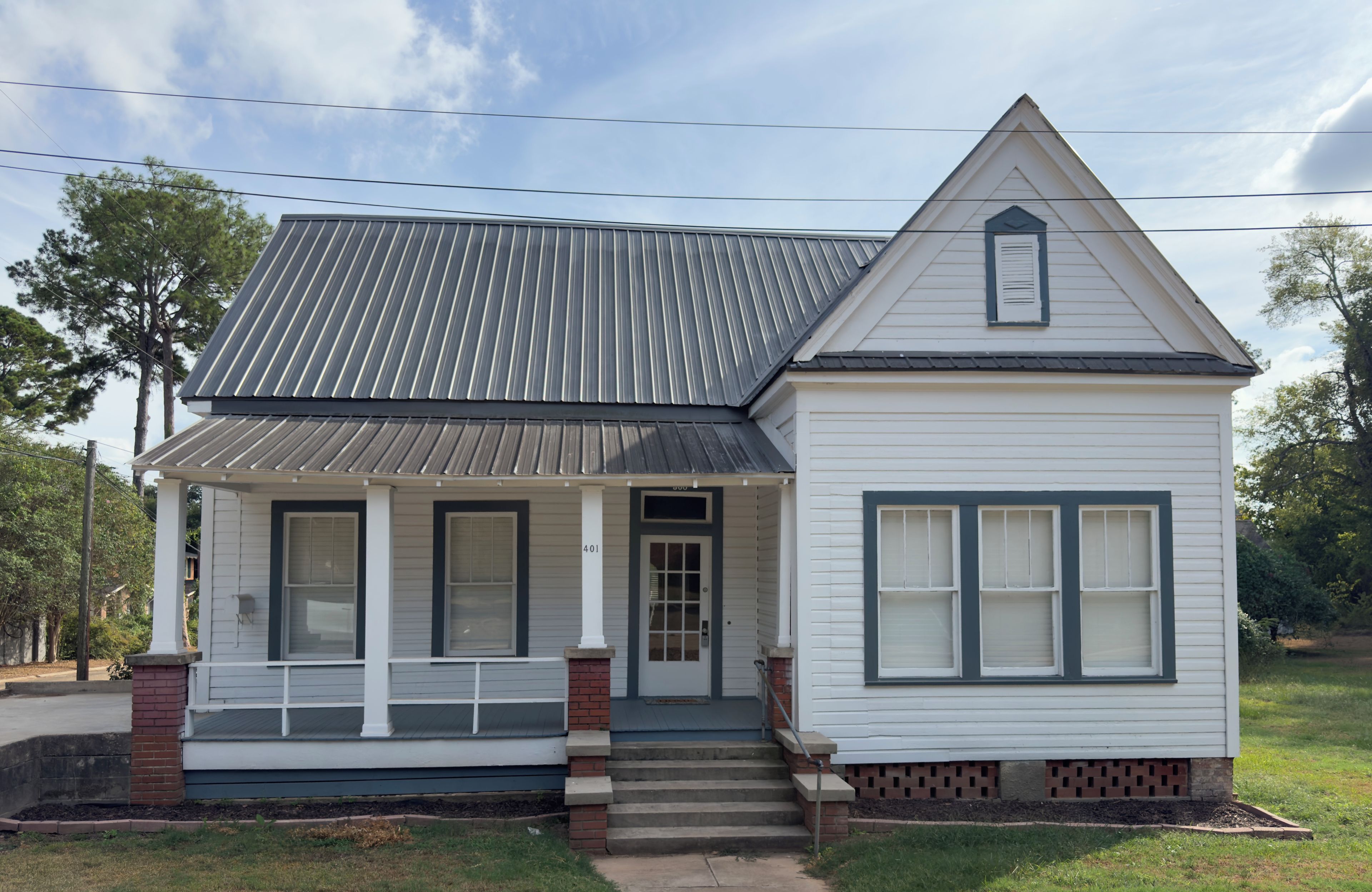 A two-story house with a front porch, a gabled roof, and a brick foundation.