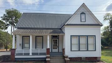 A two-story house with a front porch, a gabled roof, and a brick foundation.