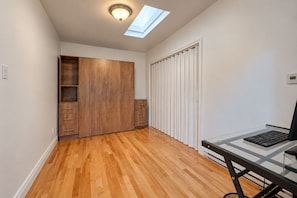 A room with a wooden wardrobe, a glass desk with a computer, and a skylight. - Spacious and Modern, Close to Metro and Amenities (Montréal)