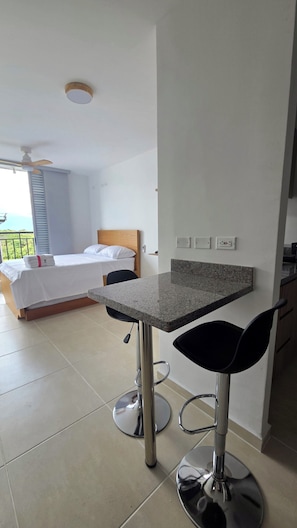 Ein Hotelzimmer mit einem Bett, einer kleinen Küchenzeile und einem Balkon.