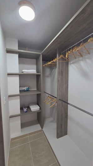 Ein begehbarer Kleiderschrank mit Holzböden, einer Kleiderstange und einem Fliesenboden.