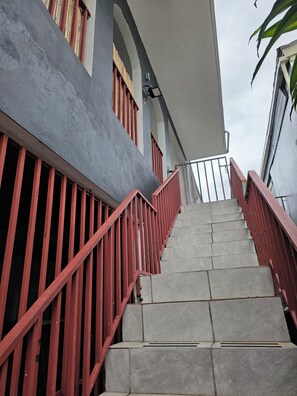 A staircase with red railings leading to a building with a grey facade and a white overhang. - Nice and accessible apartment in San Juan area, very walkable distance to malls. (San Juan)