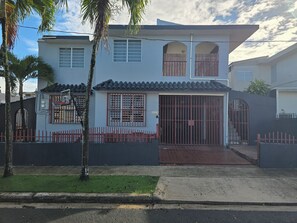 A two-story house with a gated entrance, a basketball hoop, and a small front yard. - Nice and accessible apartment in San Juan area, very walkable distance to malls. (San Juan)