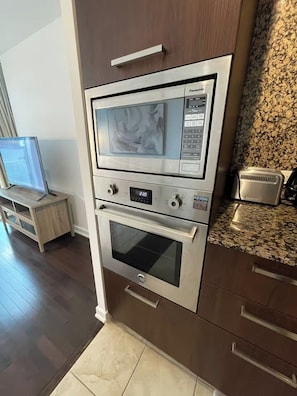 Een keuken met een inbouwoven, een magnetron en een digitaal bedieningspaneel.