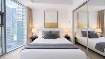 A hotel room with a large bed, two bedside tables, a mirror, and a view of the cityscape.