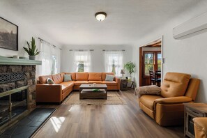 A living room with a sectional sofa, a fireplace, and a dining area. - Bright Mt. Shasta Cottage - Hot Tub, Patio & Coffee Bar (Mount Shasta)