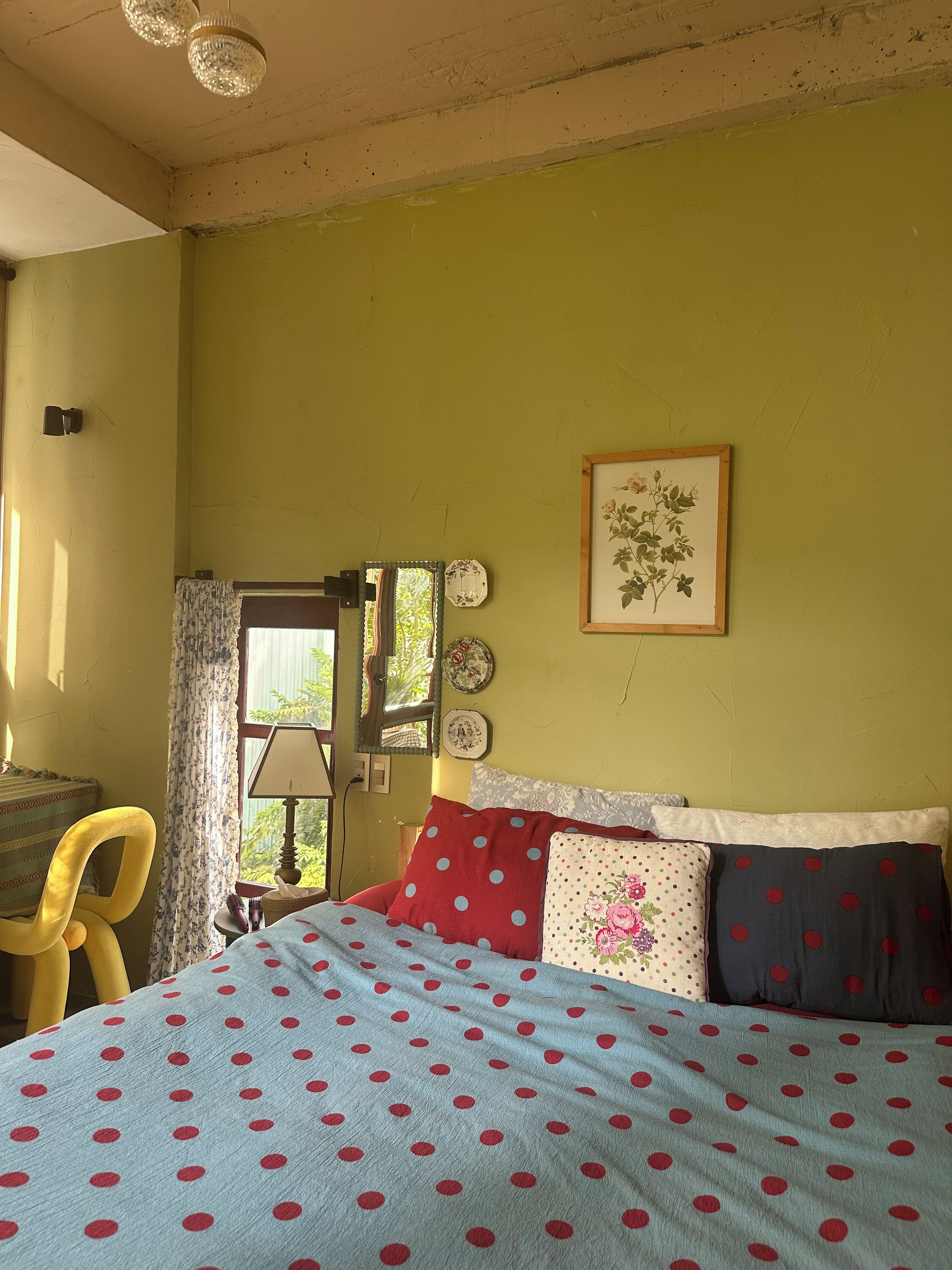 Un dormitorio con cama, una silla, un ventanal y una puerta.