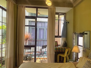 Una habitación de hotel con cama, escritorio, silla, mesa y ventana con cortinas.