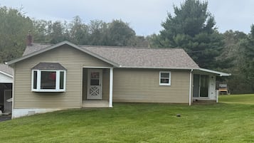 Ein eingeschossiges Haus mit Veranda, Garage und gepflegtem Rasen.