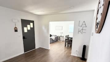 Een ruime woonkamer met houten vloeren, een zwarte deur en een eethoek met een tafel en stoelen.