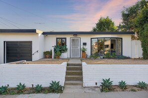 Ein modernes, zweistöckiges Haus mit Hauseingang, Garage und überdachter Terrasse.