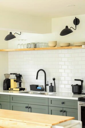 A kitchen with a white tiled backsplash, a black faucet, and a coffee maker on the counter. - Cozy getaway with beach access and great view! 7min to Nelson, 28min to ski hill (Nelson)