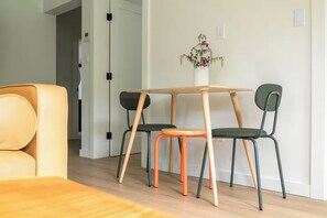 A dining area with a wooden table and chairs, a small orange stool, and a vase with flowers on the wall. - Cozy getaway with beach access and great view! 7min to Nelson, 28min to ski hill (Nelson)