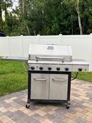 Ein tragbarer Gasgrill mit vier Brennern, einem digitalen Bedienfeld und einer seitlichen Ablagefläche.