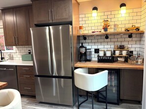 A modern kitchen with stainless steel appliances, a wooden countertop, and a bar area with a bear figurine.