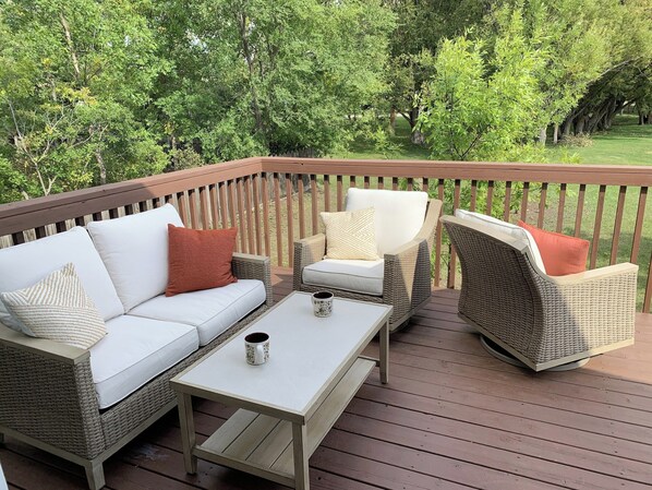 A deck with outdoor furniture, including a sofa and two chairs, and a table.