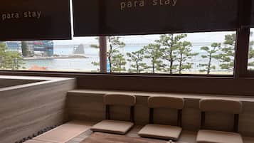 Un área de estar con vistas a un puente y al agua, que incluye una mesa de madera con teteras y un banco con cojines.