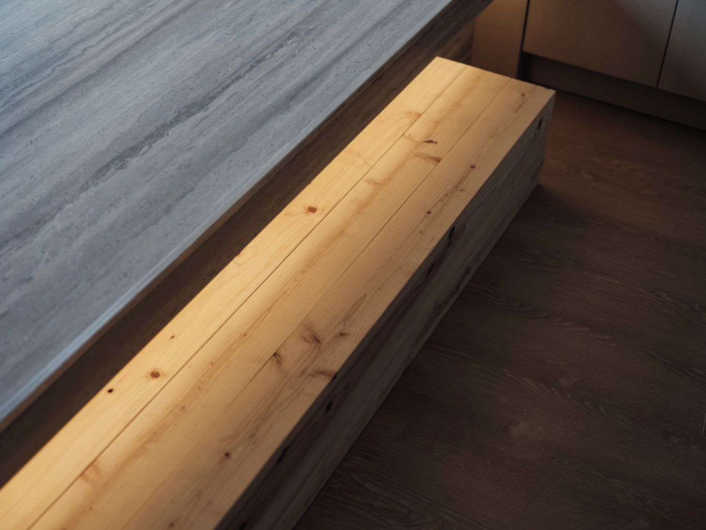 A wooden bench with a grey stone-like surface beside it.
