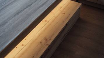 A wooden bench with a grey stone-like surface beside it.