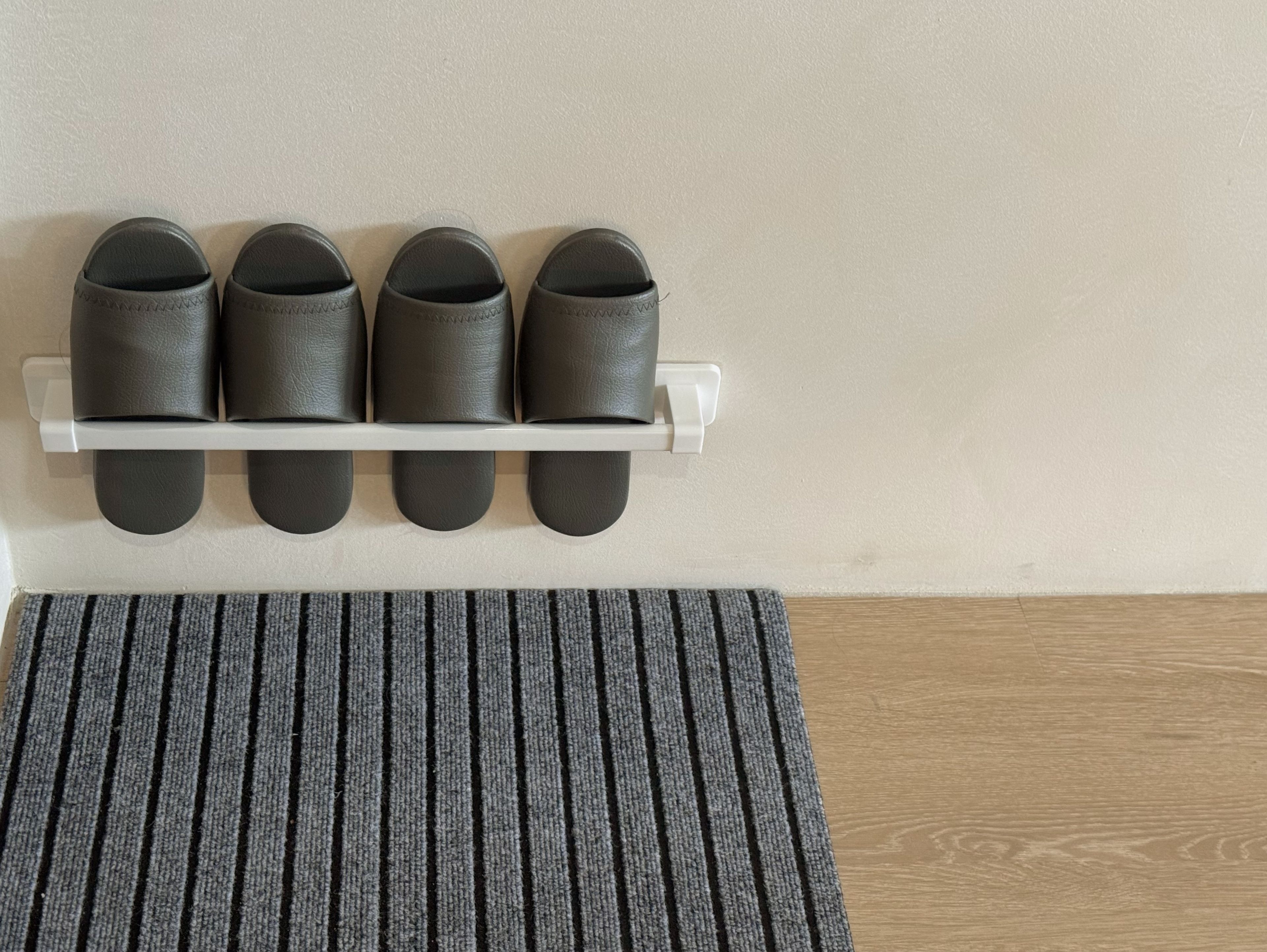 Un zapatero con cuatro pares de zapatos junto a una pared.