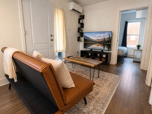 Ein Wohnzimmer mit Sofa, Couchtisch, Fernseher und Bücherregal.