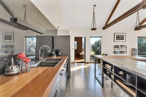 A modern kitchen with stainless steel appliances, wooden countertops, and a large island with bar stools. - Villa Rochford Kellevie (Sorell)
