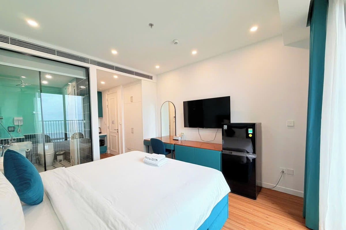 Una habitación de hotel con cama, escritorio, televisión y refrigerador.