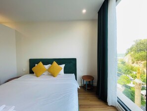 A hotel room with a bed, a small round table, and a view of greenery outside. - VietStay Vietnam (Phu Quoc)