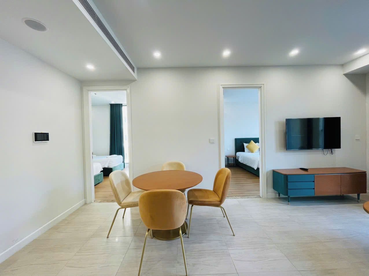 A modern hotel room with a dining area, a TV, and a bed.