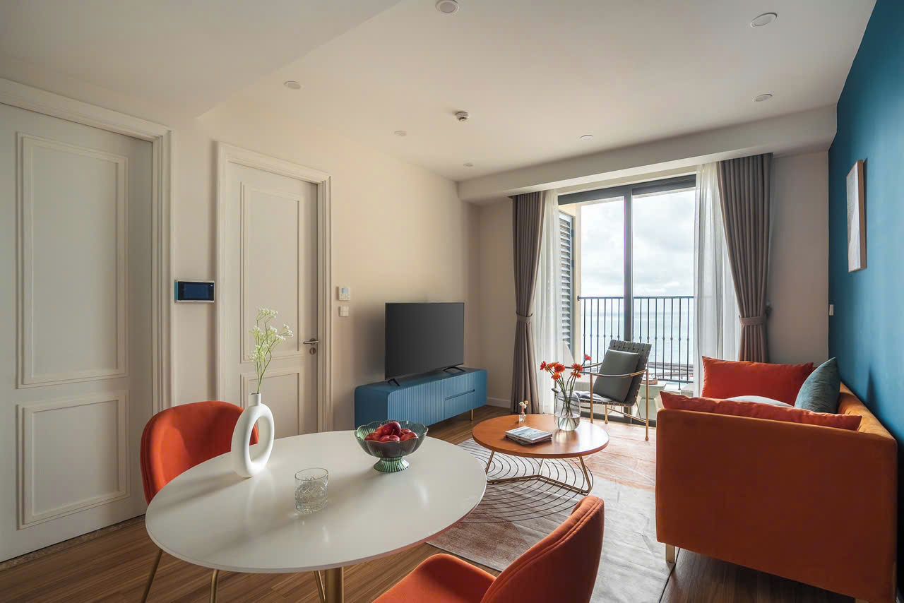 Una sala de estar moderna con comedor, televisor y balcón con cortinas.