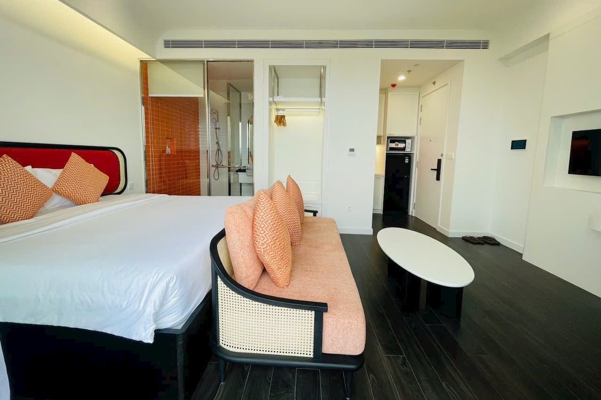 Una habitación de hotel con cama, sofá, una mesita y un espejo.